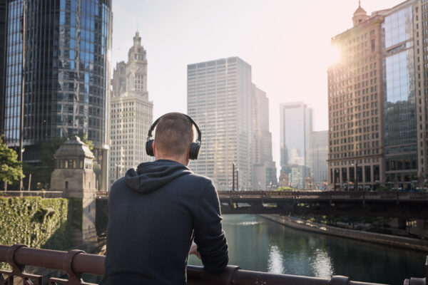 Man wearing headphones overlooking city skyline while listening to a business podcast—Talk Nerdy to Me, hosted by The William Stanley Group
