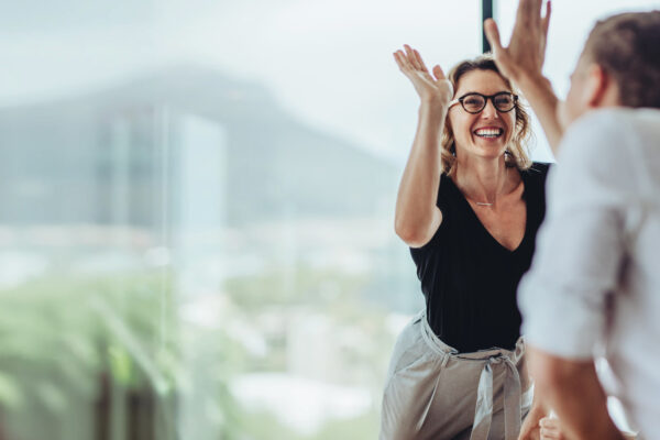 Smiling professional woman celebrating good news in a modern office setting, representing The William Stanley Group’s TBBW feature announcement.