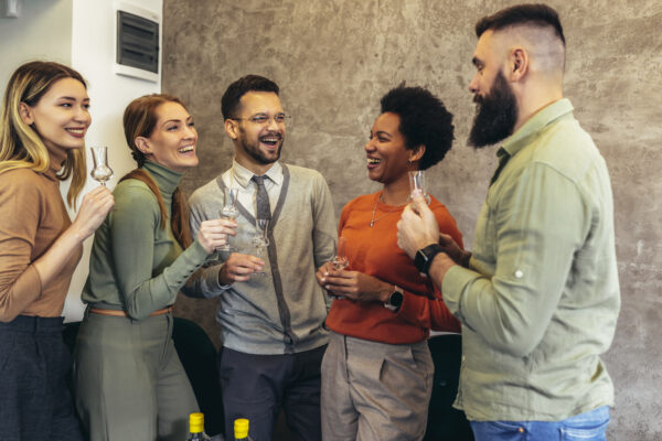 Group of young professionals smiling and clinking glasses at a networking event, symbolizing growth and recognition. Image used to highlight The William Stanley Group’s feature by Brian Hartz in The Business Observer.