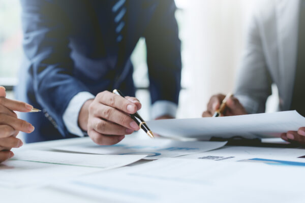Close-up of professionals reviewing financial documents and contracts, representing The William Stanley Group’s Business Insider feature on student loan deferment strategies.