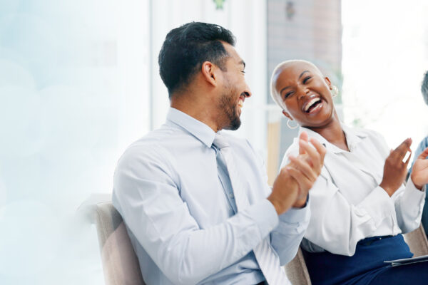 Business professionals laughing and engaging during a team meeting, illustrating The William Stanley Group’s HubSpot feature on hiring for personality fit.