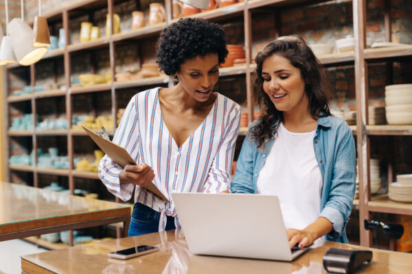 Two entrepreneurs reviewing inventory metrics on a laptop in a boutique store, illustrating the importance of understanding the cash conversion cycle for operational efficiency