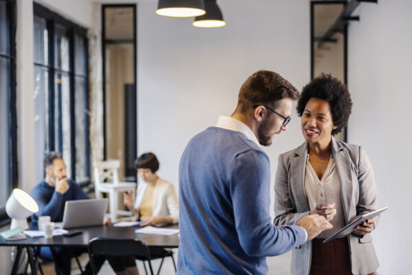 Two professionals smiling and reviewing financial documents in a collaborative office space, showcasing The William Stanley Group’s CFO Dive feature.