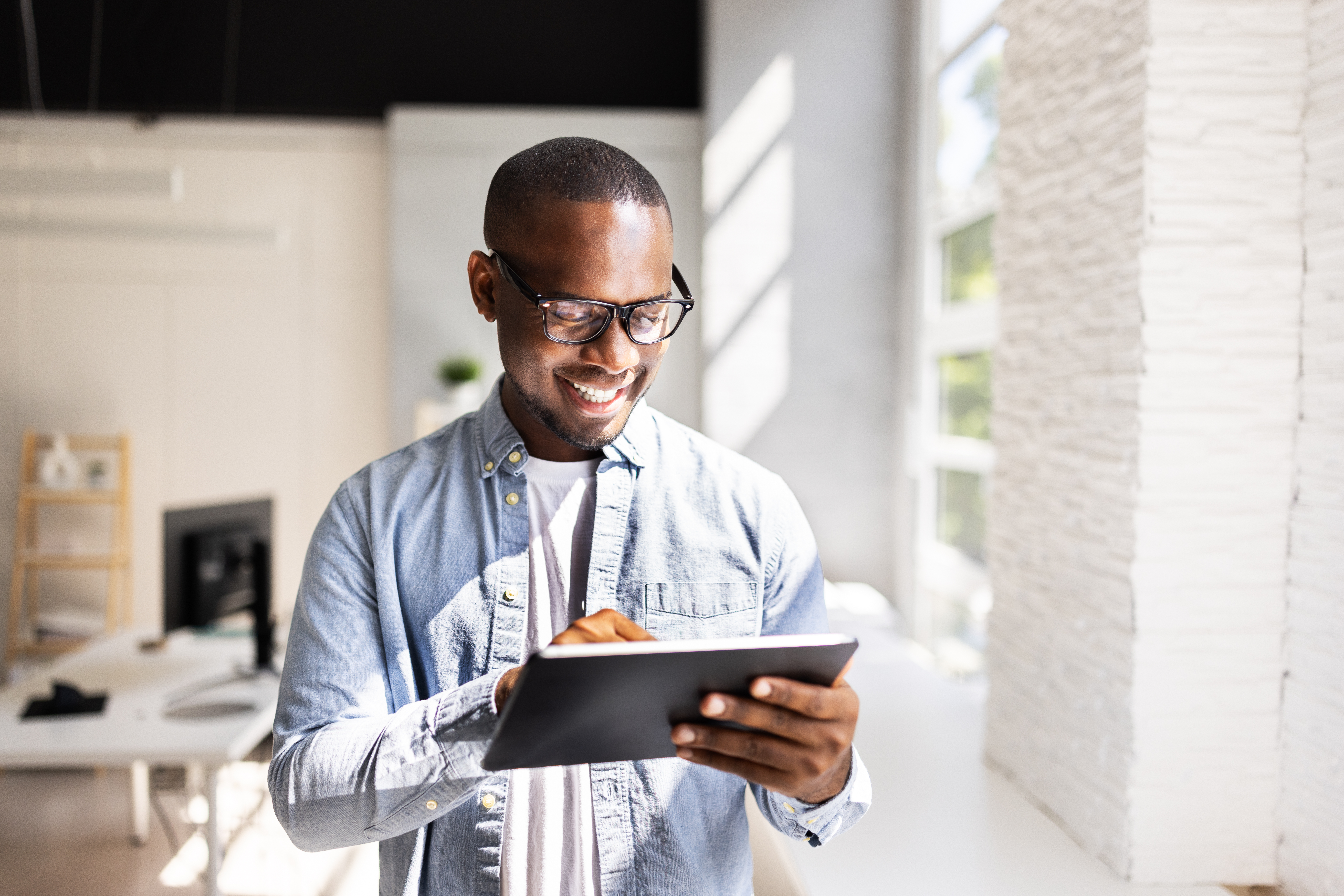 Smiling professional reviewing data on a tablet in a bright modern office, representing clarity and control through 13-week rolling cash flow forecasting