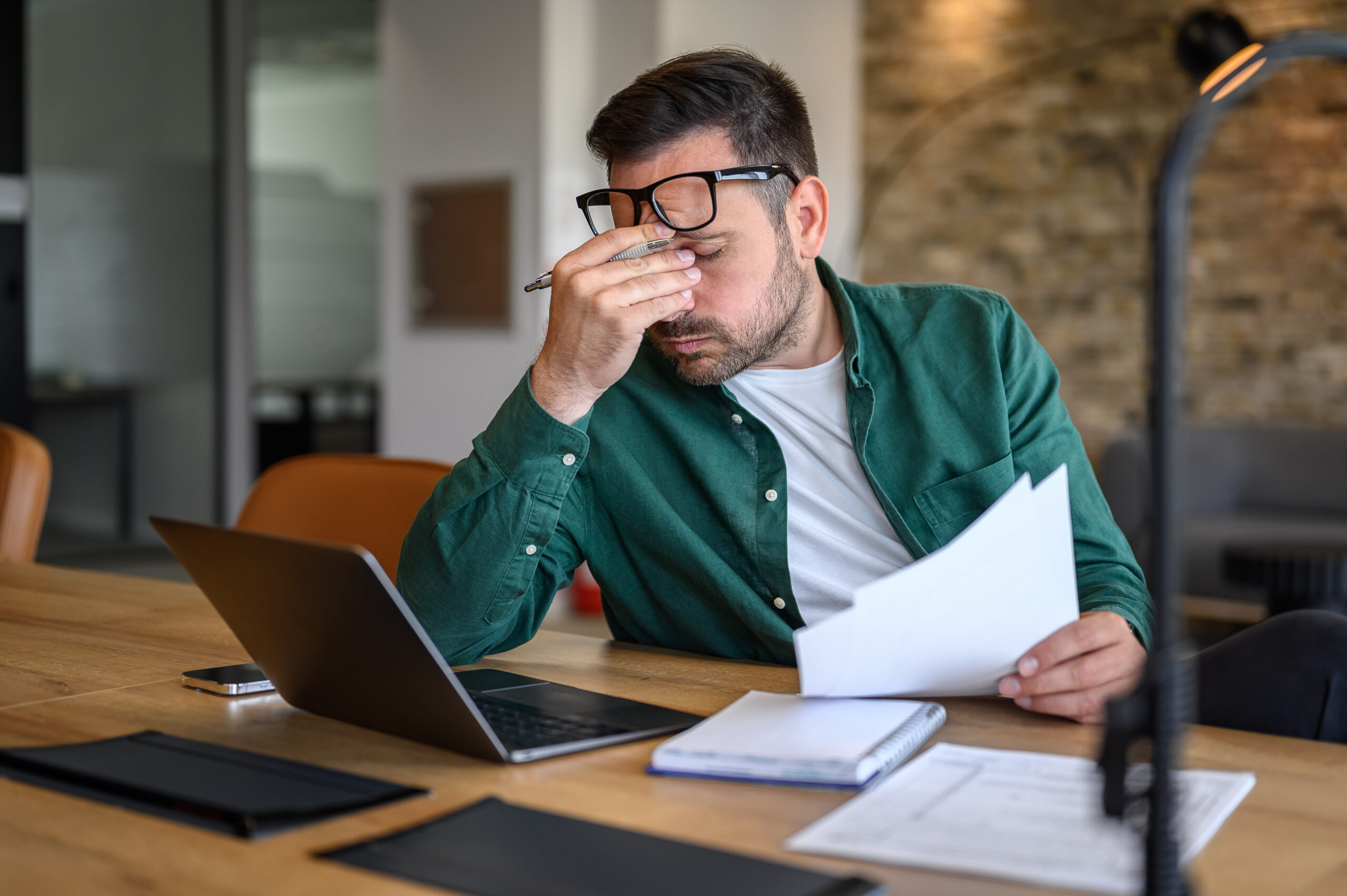 Concerned man reviewing documents at his desk, symbolizing The William Stanley Group’s Best Products feature on how to cancel a credit card responsibly.